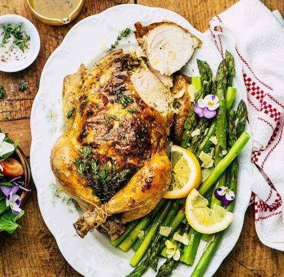 Tablett mit gebratenem Hähnchen, daneben gegarter grüner Spargel