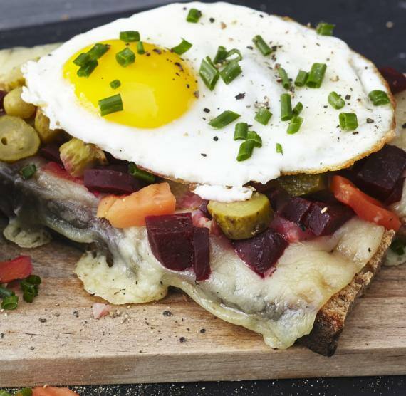 Belegtes Brot mit Spiegelei und Gemüse auf einem Holzbrettchen