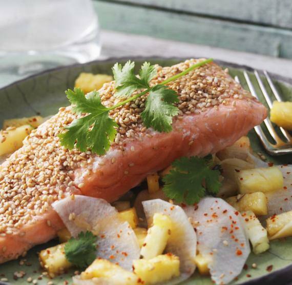 Lachsstück neben Salat aus Rettich und Ananas auf einem Teller
