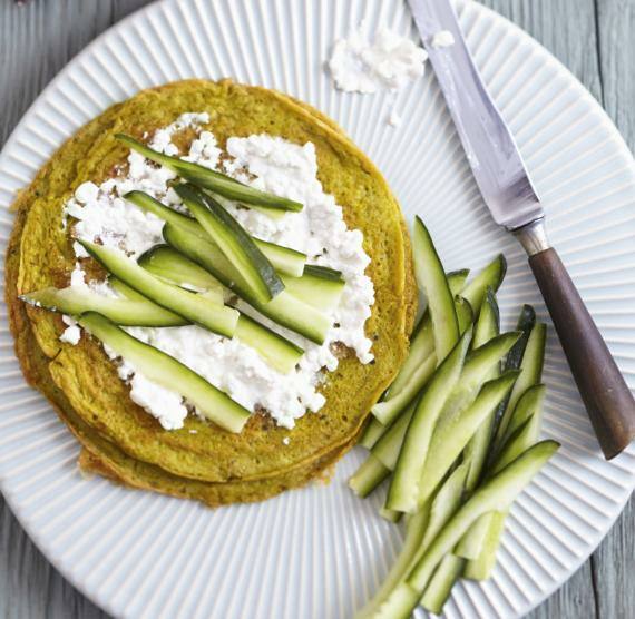 Pfannkuchen mit Hüttenkäse darauf, daneben Gurkensticks auf einem Teller