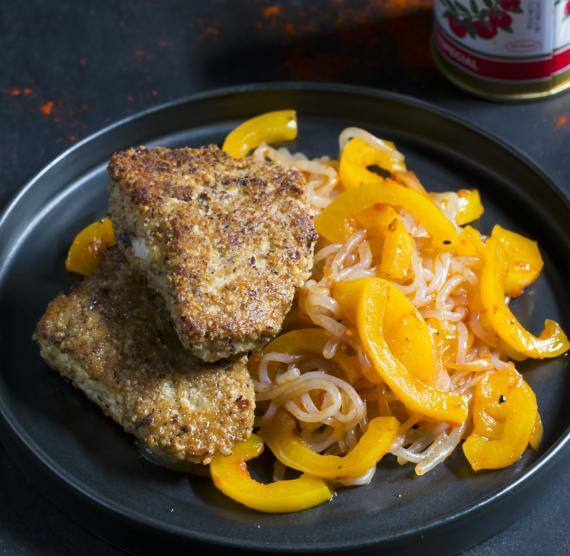 Paniertes Hähnchenstück eben Nudeln mit Paprika auf einem Teller