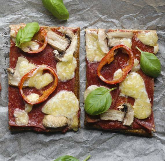 Pizzastücke auf Backpapier garniert mit Basilikum