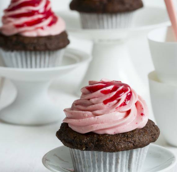 Cupcakes mit dunklem Teig und rosa Creme auf einem Tisch