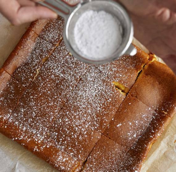 Rechteckiger Käsekuchen wird mit Puderzucker bestäubt