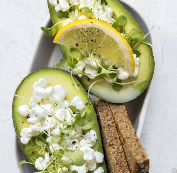 Halbierte Avocado gefüllt mit Hüttenkäse und Sprossen auf einem Tisch