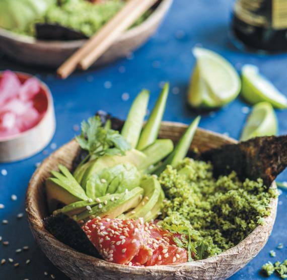 Schale mit Brokkolireis, Lachs und Avocado auf einem Tisch