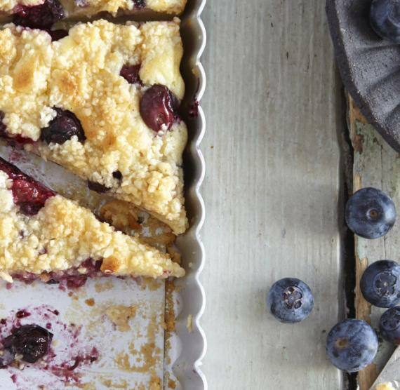 Kuchen mit Blaubeeren angeschnitten auf einem Holztisch