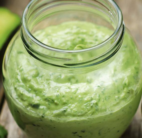 Grünes Dressing in einem Schraubglas auf einem Holztisch