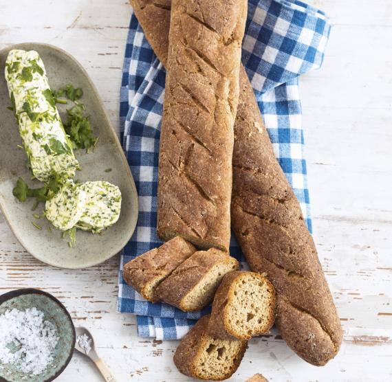 Baguettestangen auf einem Küchentuch daneben Kräuterbutter