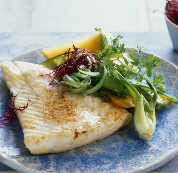 Fischfilet auf einem Teller daneben Salat aus Pak Choi und Kaki