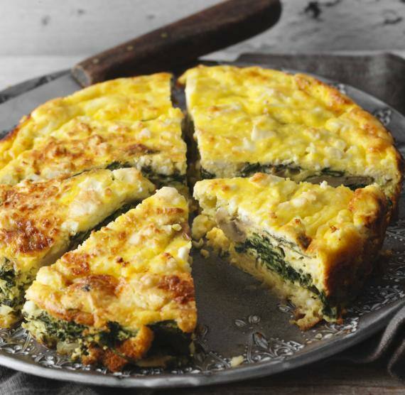 Quiche auf einem Teller in fünf Teile geschnitten steht auf einem Holztisch