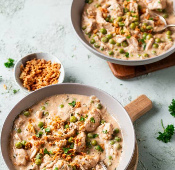 Hähnchen‑Erbsen‑Topf angerichtet in zwei tiefen Tellern auf einem Tisch