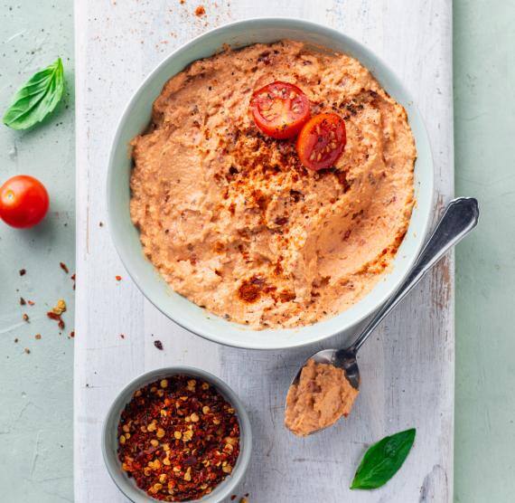 -Tomate‑Mozzarella‑Dip in einer Schale auf einem Holzbrett