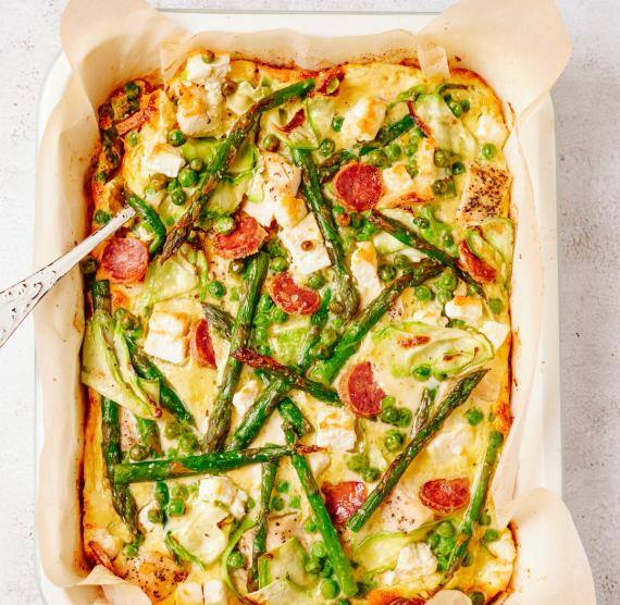 Spargelauflauf mit Hähnchen, Zucchini, Erbsen, Salami und Feta in einer rechteckigen Auflaufform